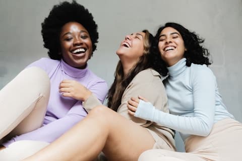 Three friends leaning on each other, laughing