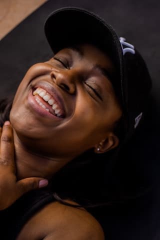 A woman in a cap laughing, eyes closed